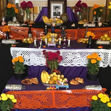 Mexican offering for the Day of The Dead with food, flowers, pictures and religious symbols.